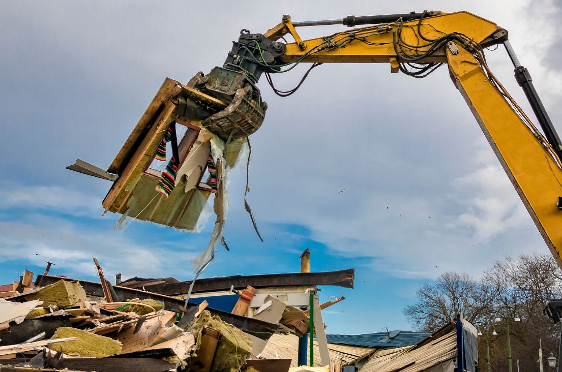 a photo of Excavating and Grading Waukesha WI A mechanical claw demolishing a wooden structure with debris scattered around a photo of Excavating and Grading Waukesha WI A mechanical claw demolishing a wooden structure with debris scattered around