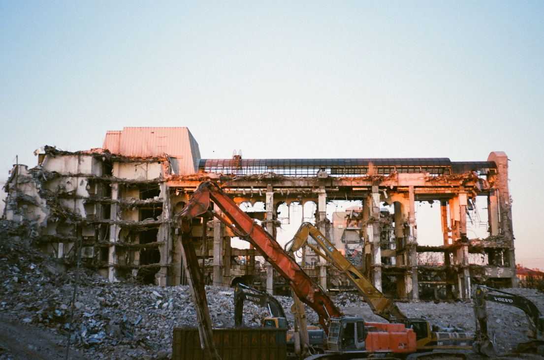 Excavating & Grading New Berlin WI - Demolition of a large industrial building at dusk with excavators.